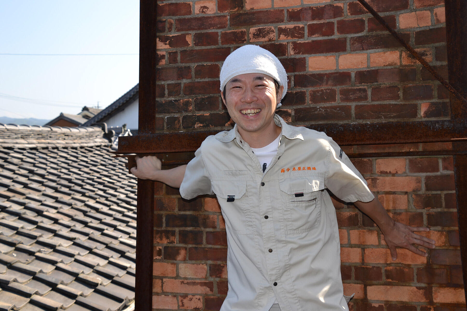レンガ造りの煙突を背に少年のような笑顔を見せる大西さん