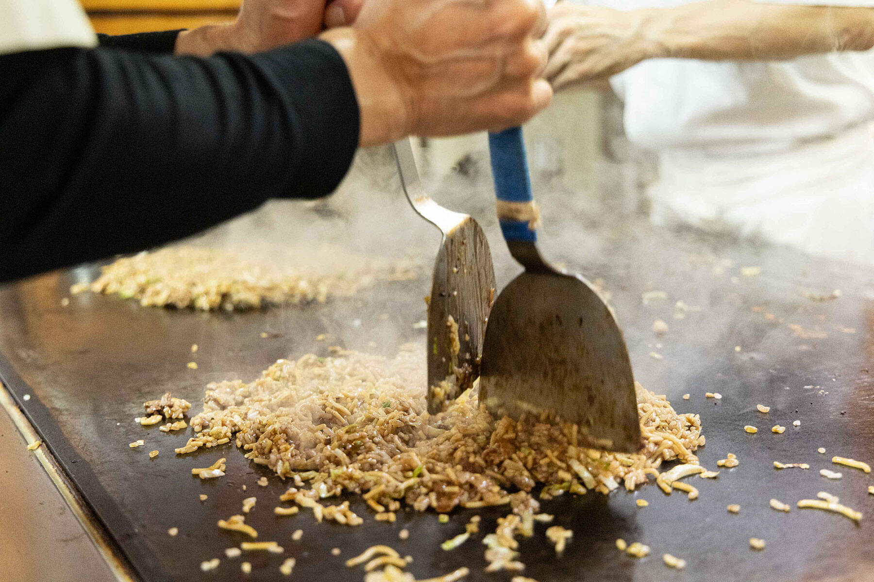 大きなテコを使い「やきめし」の具を炒めながら刻んでいく