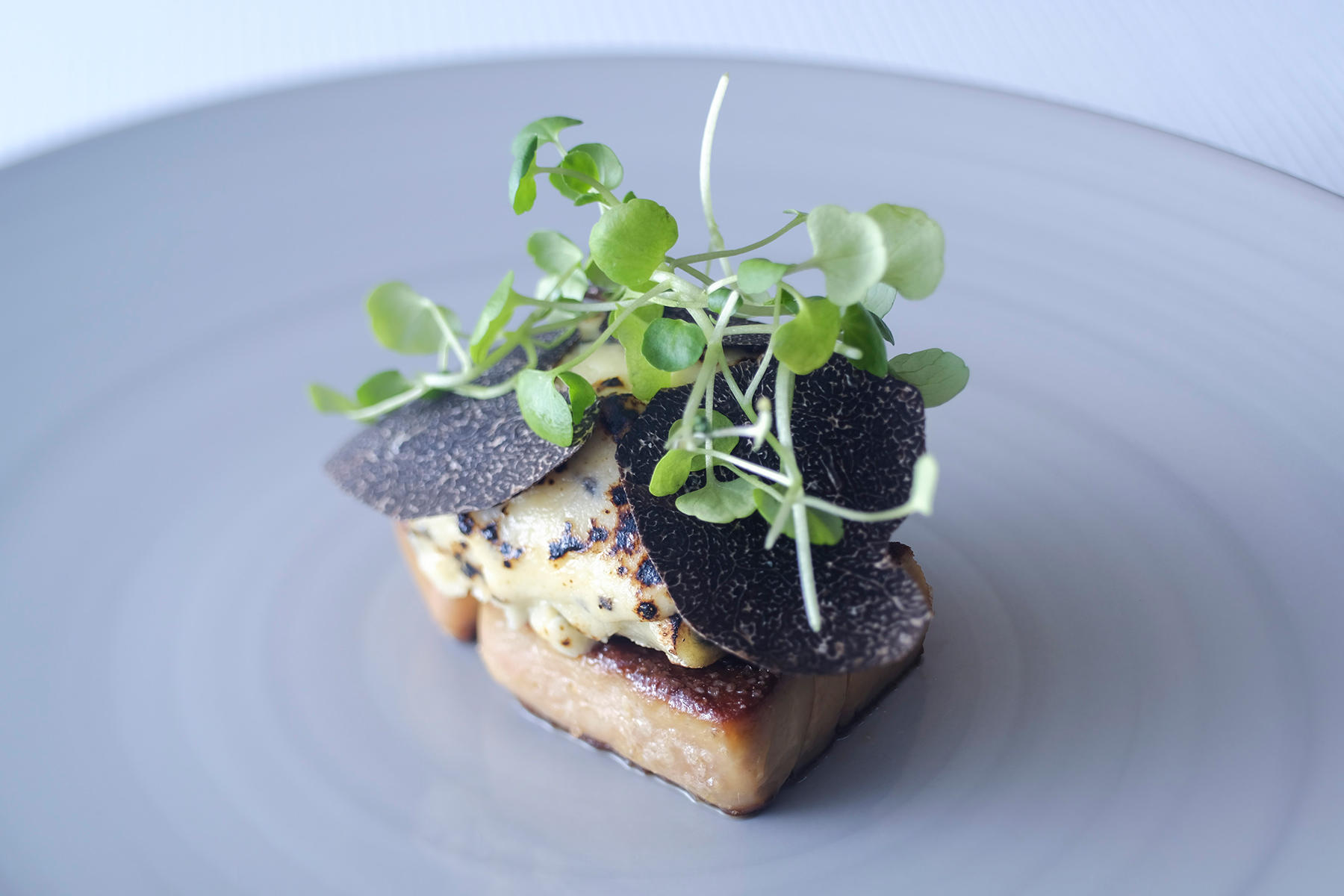 黒トリュフコースの3品目。フランスでは家庭料理としてお馴染みのアンディーブとハムのグラタンをガストロノミー的な一皿に昇華させている。黒トリュフをのせるだけでなく、ベシャメルソースの中にもトリュフのジュースと黒トリュフをたっぷり加えている。スペッツリというアルザスのパスタ生地でアンディーブとハムを巻き、モルネーソースをかけてグラチネ。カネロニのように仕上げている。