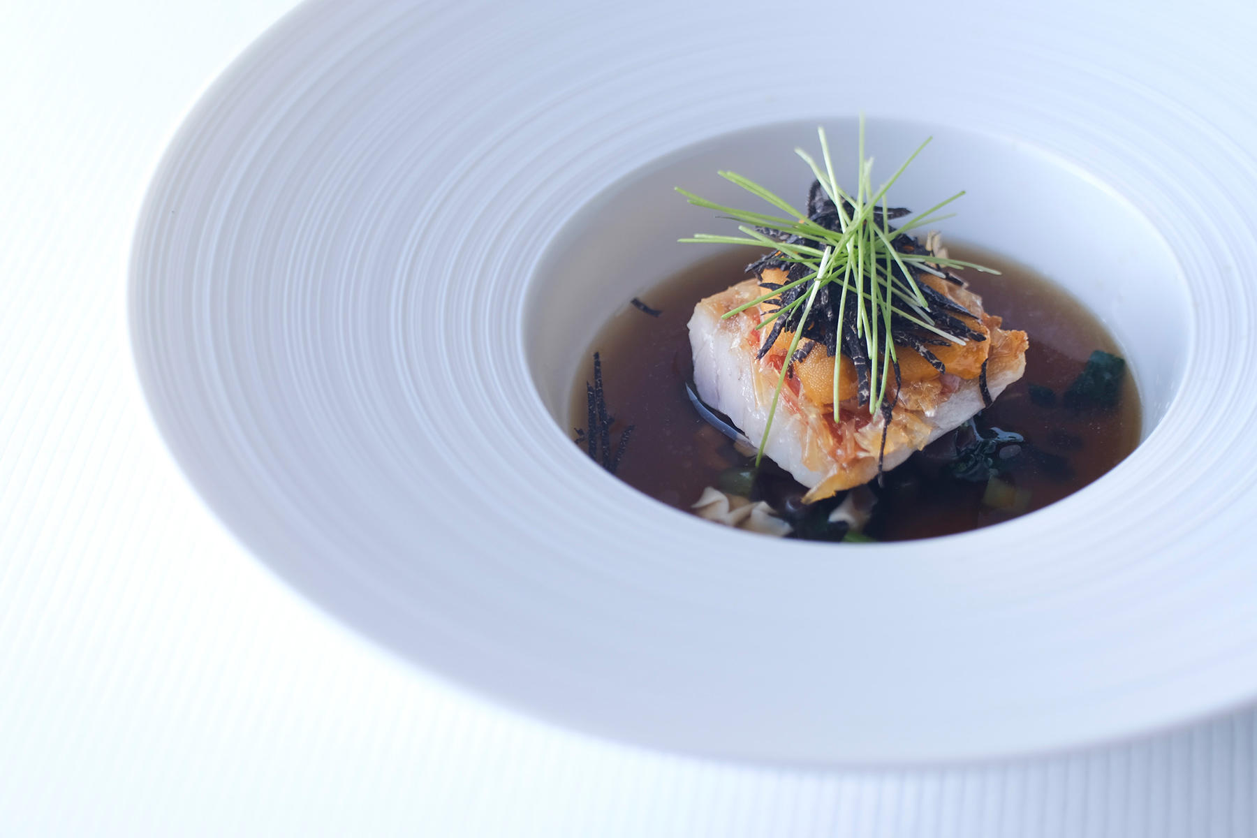 黒トリュフコース4品目に登場する魚料理。肉厚にカットした金目鯛は、ふわっと軽やかな身質とサクサクの皮、ふたつの食感のコントラストが楽しい。マッシュルームのコンソメがトリュフの香りを引き立てる。