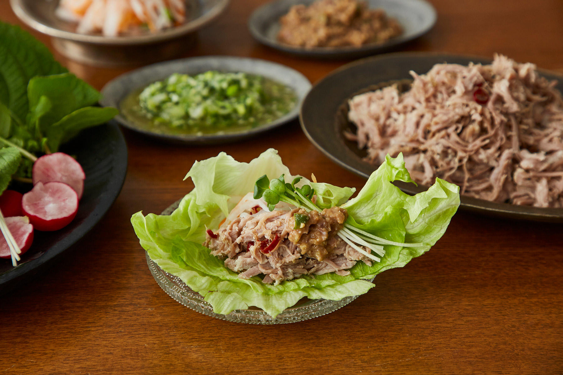 パクチー、えごまの葉、かいわれ菜、レタス、ラディッシュなどの野菜を添えて、コンポークとお好みのたれを巻いてどうぞ。