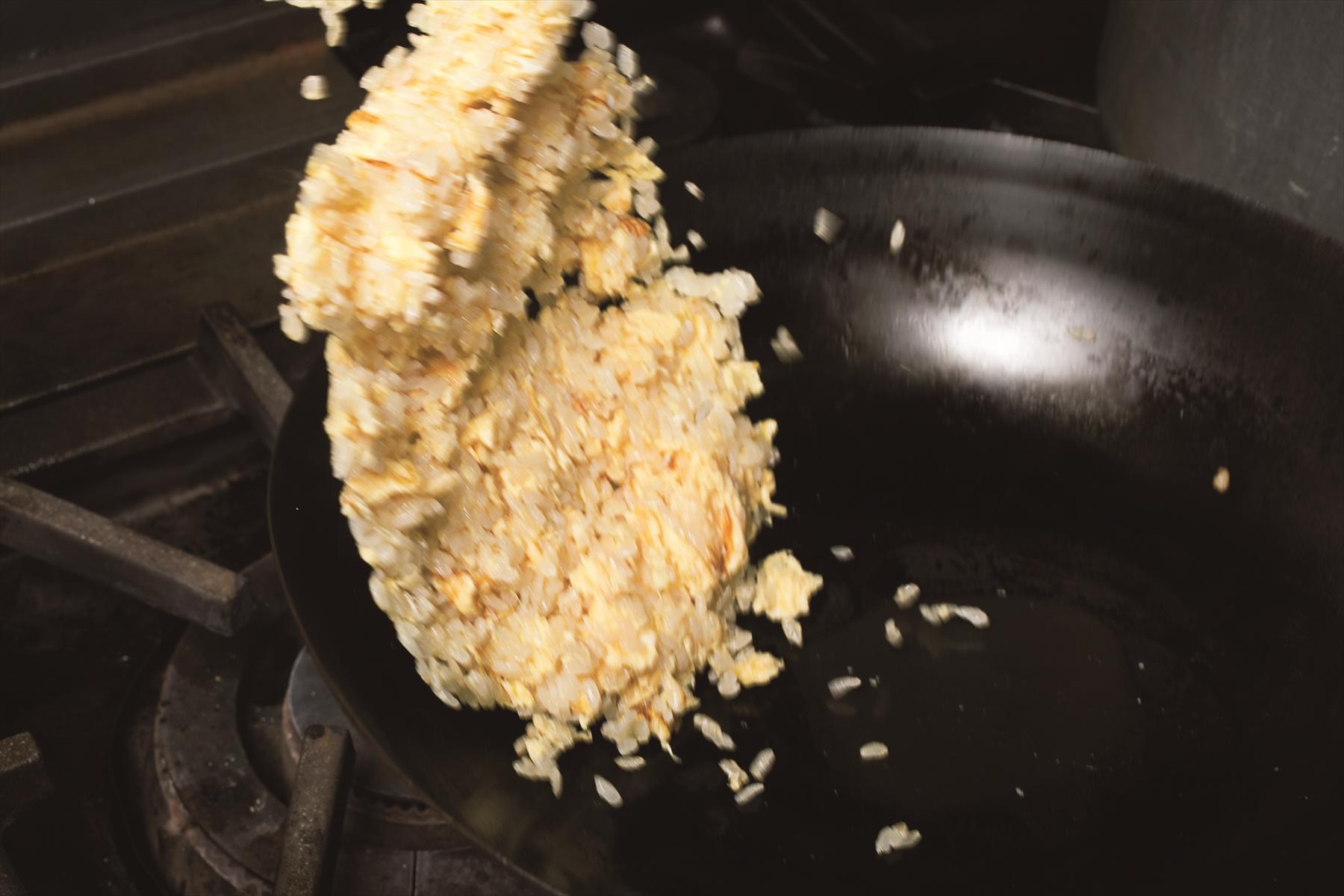 鍋をあおるときはごはんの間に空気を入れる要領で。“広げる”“あおる”を繰り返すことで、ごはんに卵がきれいにコーティングされていく。