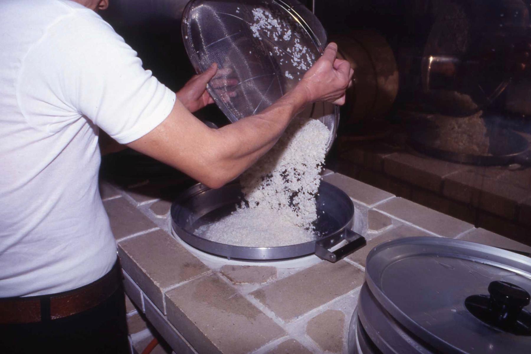 吸水の終わった米を釜に入れる。体に染み付いた動きは、鮮やかに米を運ぶ。