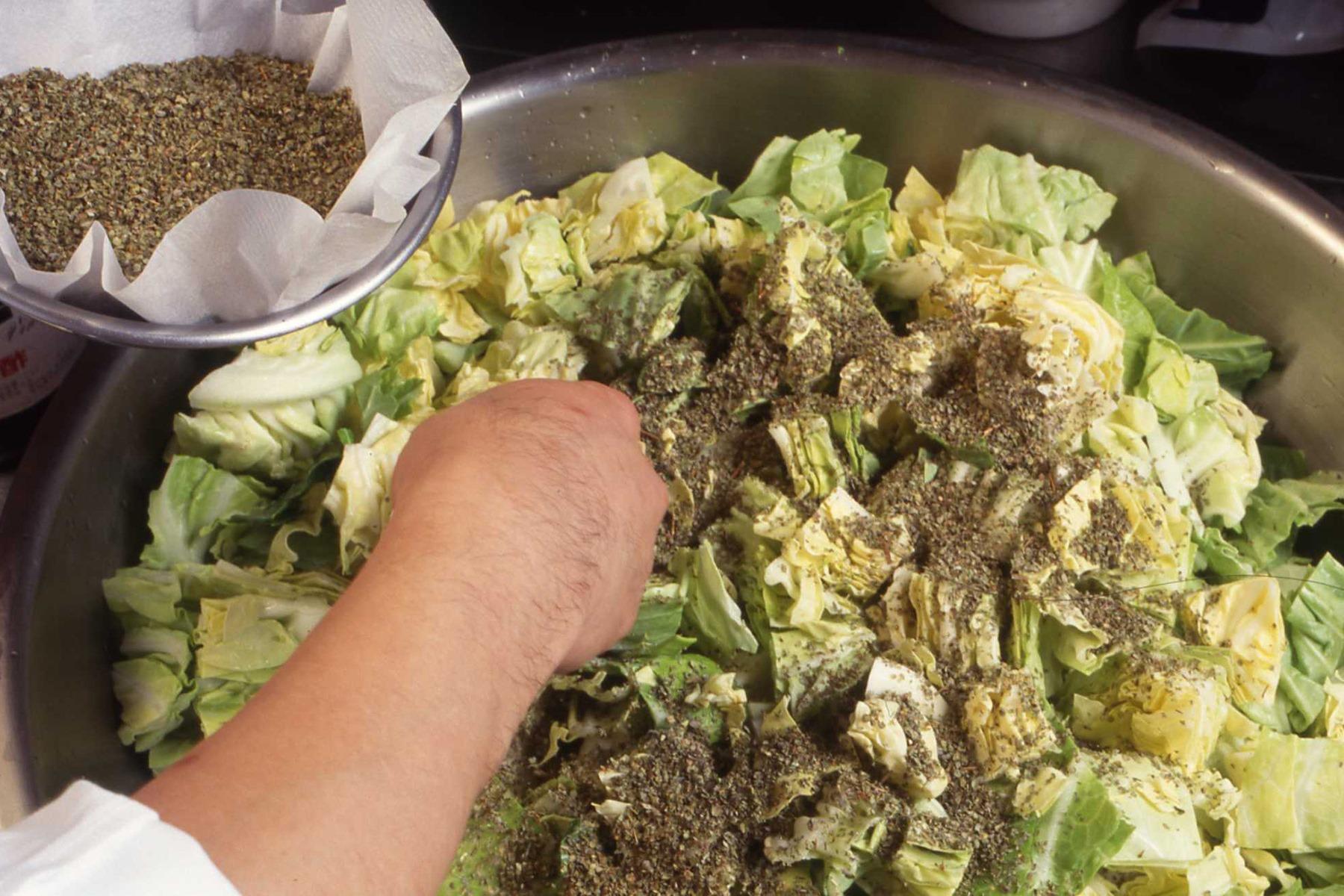 キャベツをボウルに入れ、マジョラムと塩をふりかけ、最後に酢を加える。