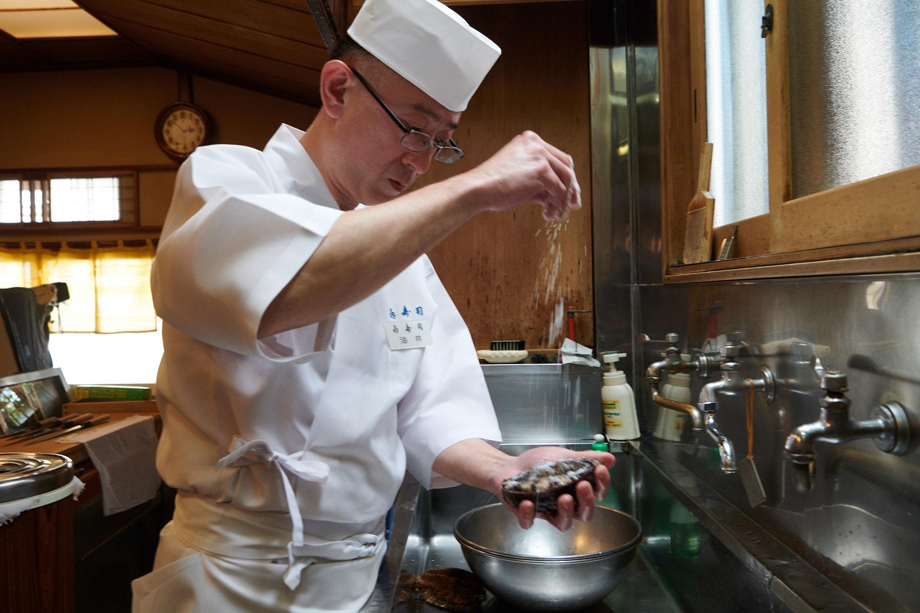 鮑に塩を振って締める「㐂寿司」四代目の油井一浩さん。