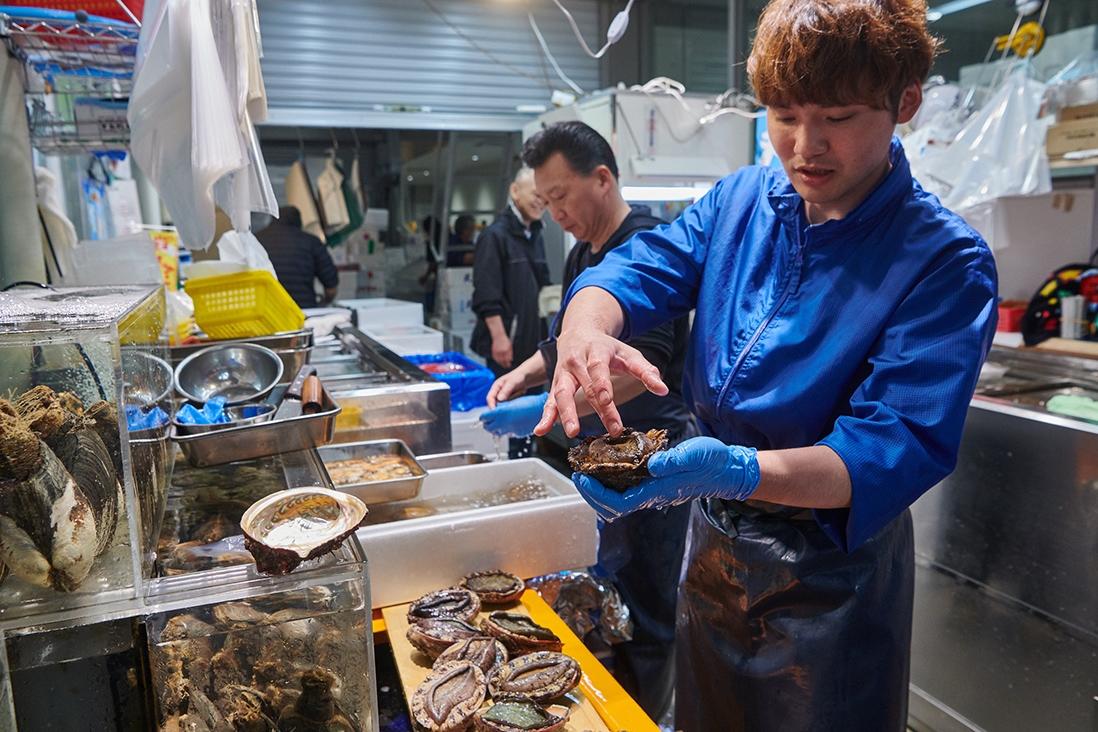 「丸佳」の山岸佳弘さん。細やかによい鮑の見分け方を説明してくれた。
