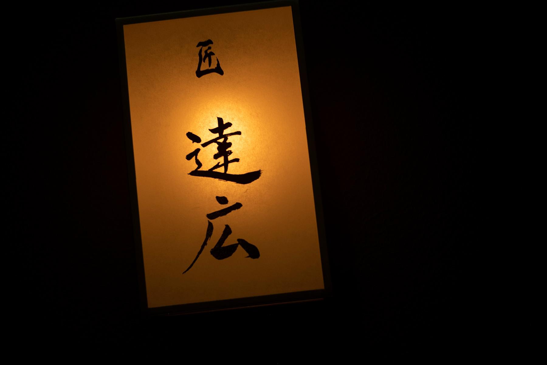 雑居ビルが並ぶ中、シンプルな檜の引き戸と小さな筆文字の看板がオーラを放つ。