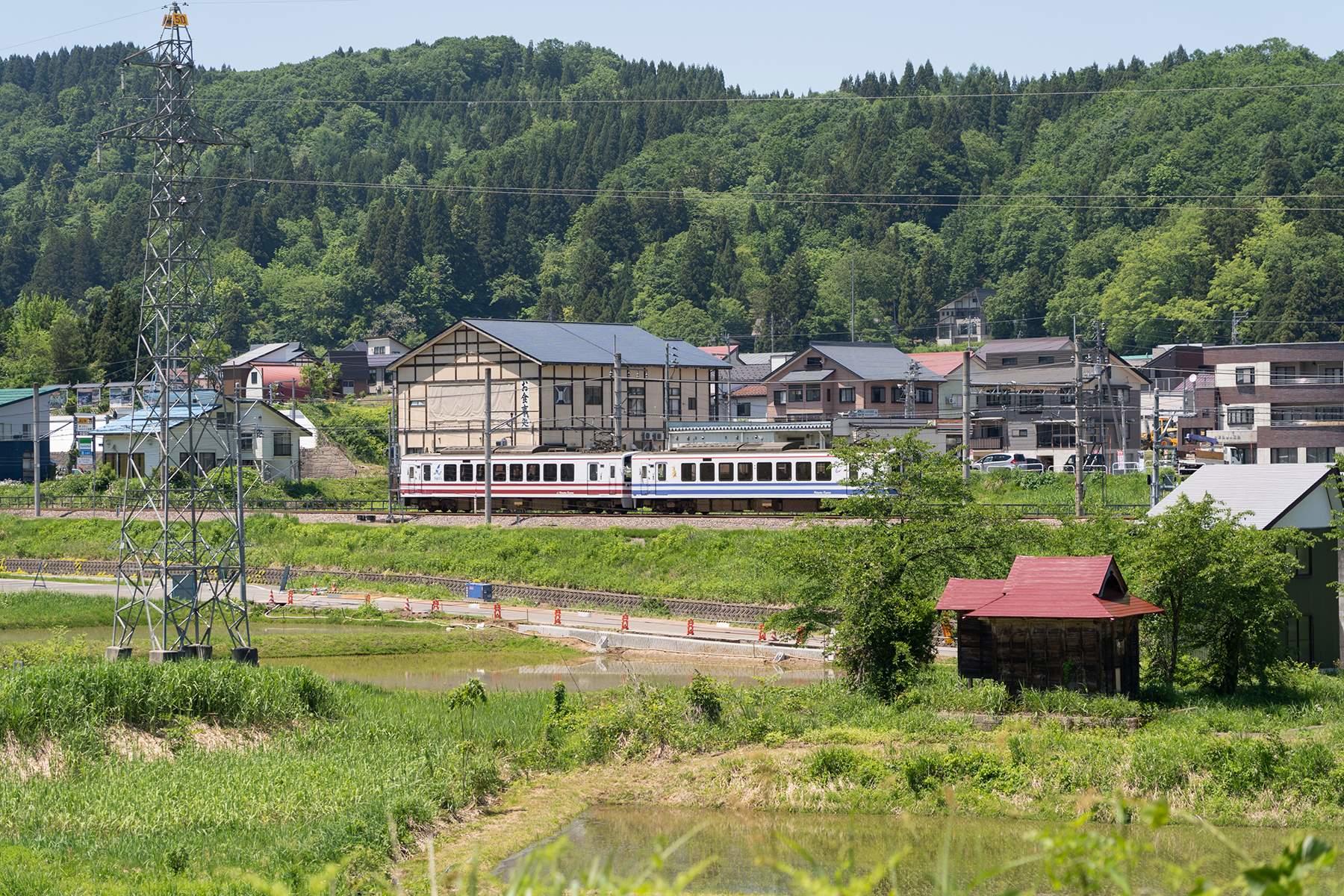 棚田から遠くを望めば、のどかな田園風景が広がっている。2両編成のほくほく線車両が右から左へすーっと走って、視界から消えていった。
