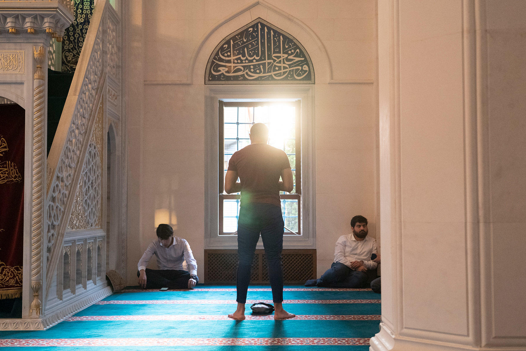 夕日が差し込む礼拝堂で、メッカの方角に向かってサラートするムスリムの男性