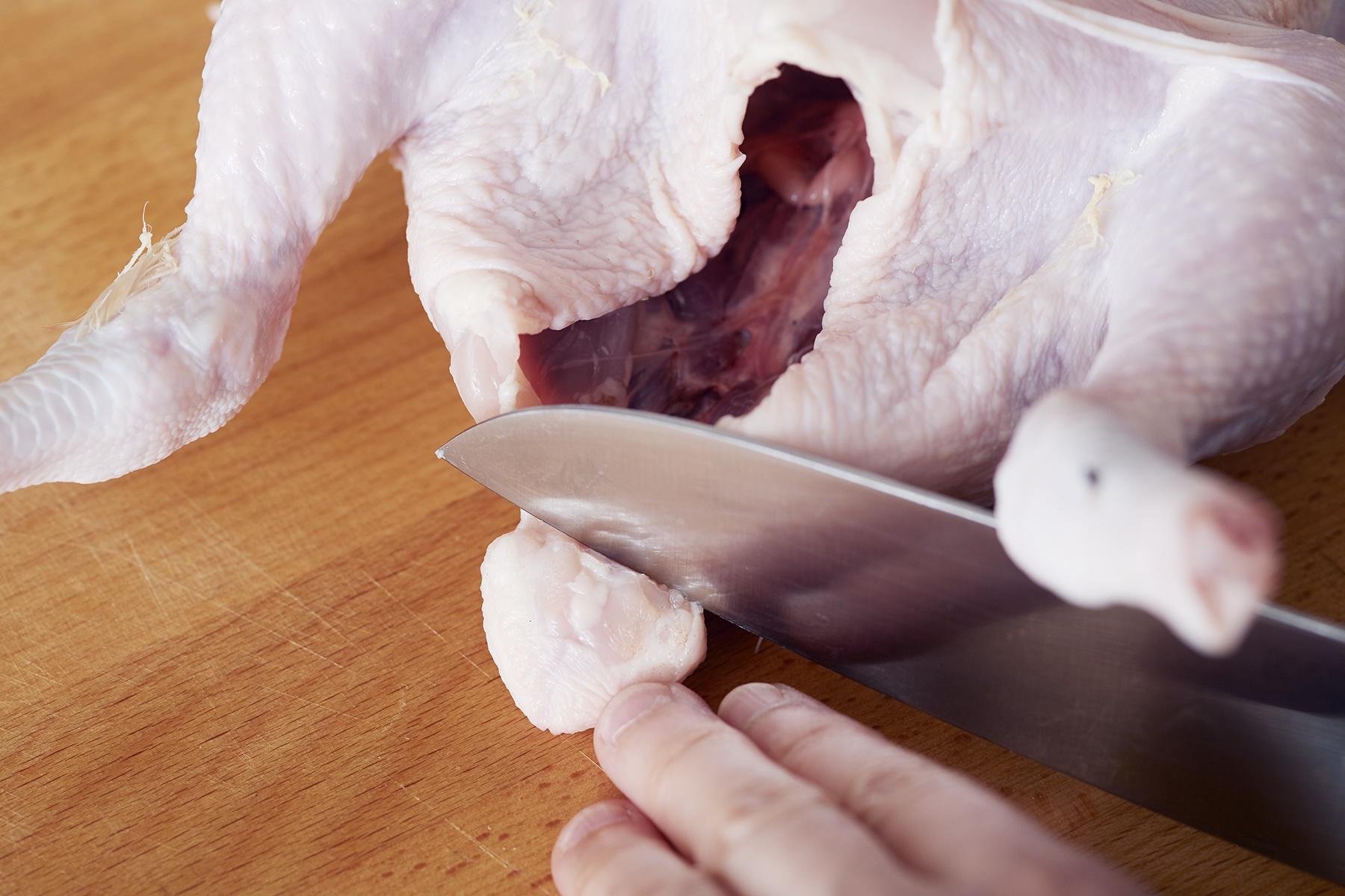 鶏の尻にある尻尾のような脂肪(ぼんじり)を包丁で切る。