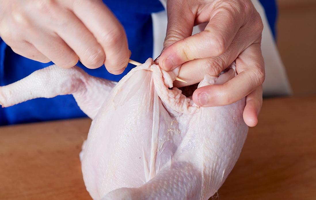 2、鶏の腹側から、左右の皮を交互に竹串で突き刺していく。