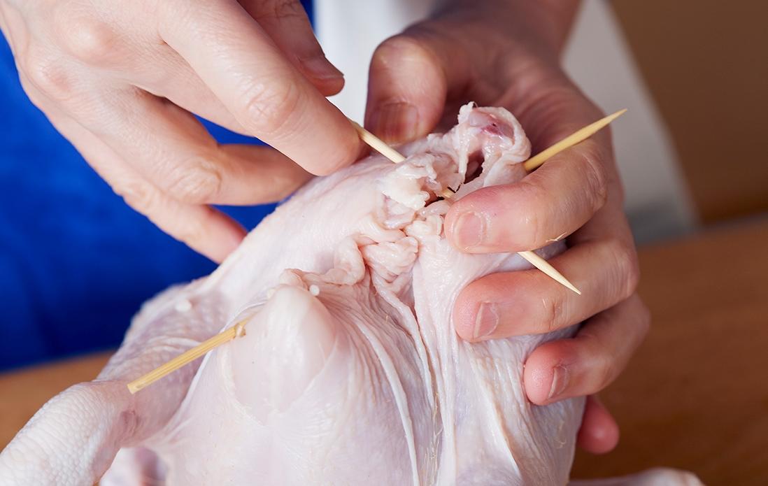 4、背中側の縫いづらい箇所は、左右の皮を寄せ合わせて、別の竹串で突き刺す。竹串の長さが余っている部分は、はさみで切り落とす。