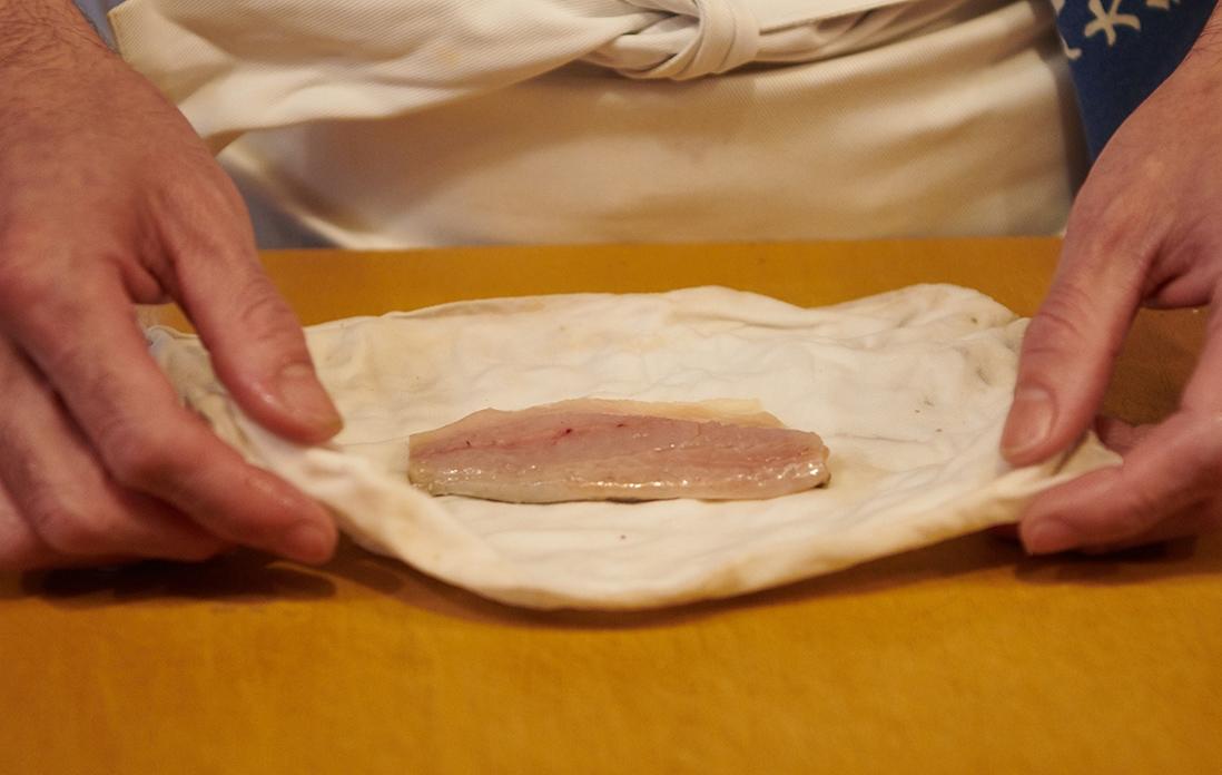 酢から引き上げた鯵をふきんで包む。