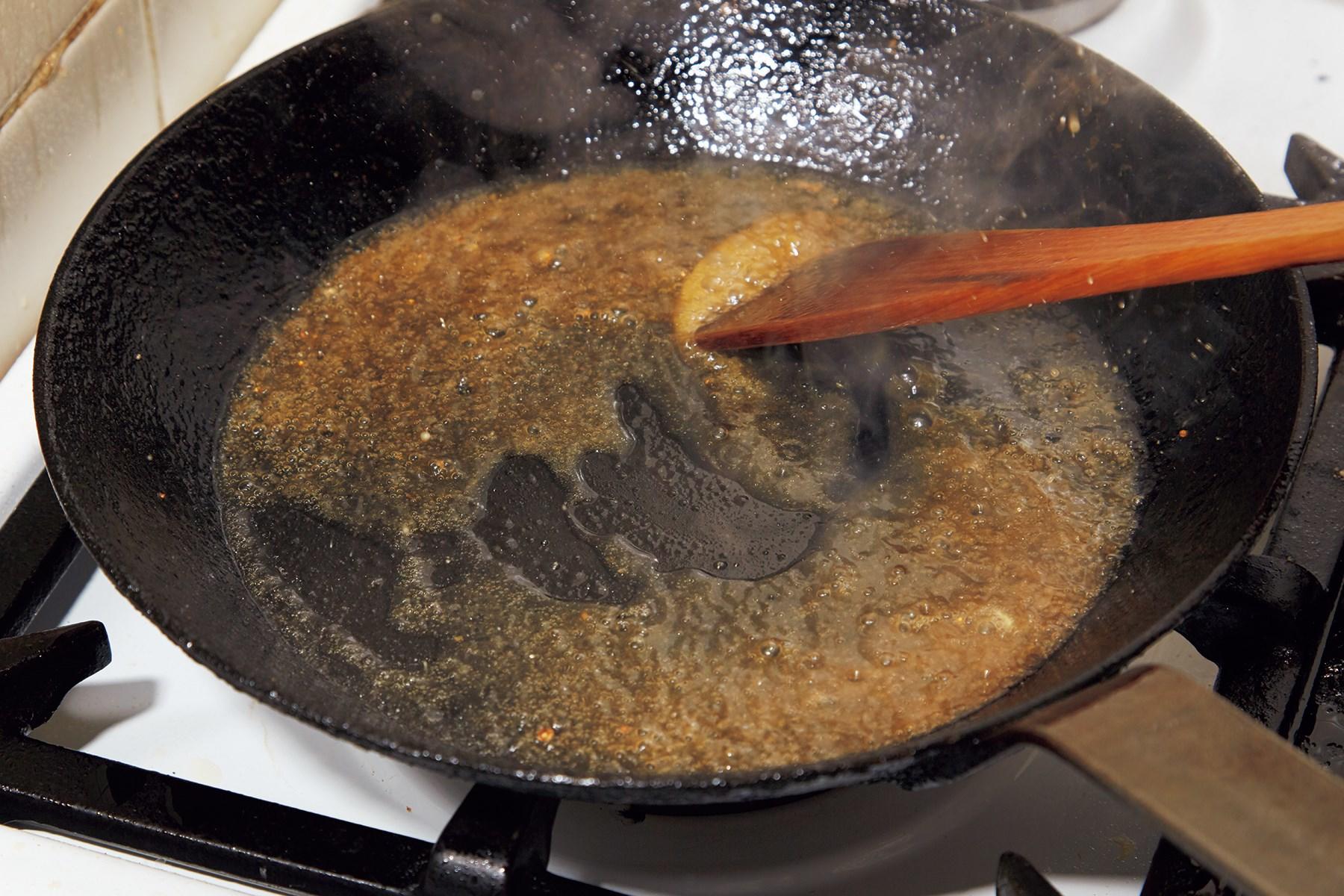 ヘラでフライパンについた旨味をこそげる