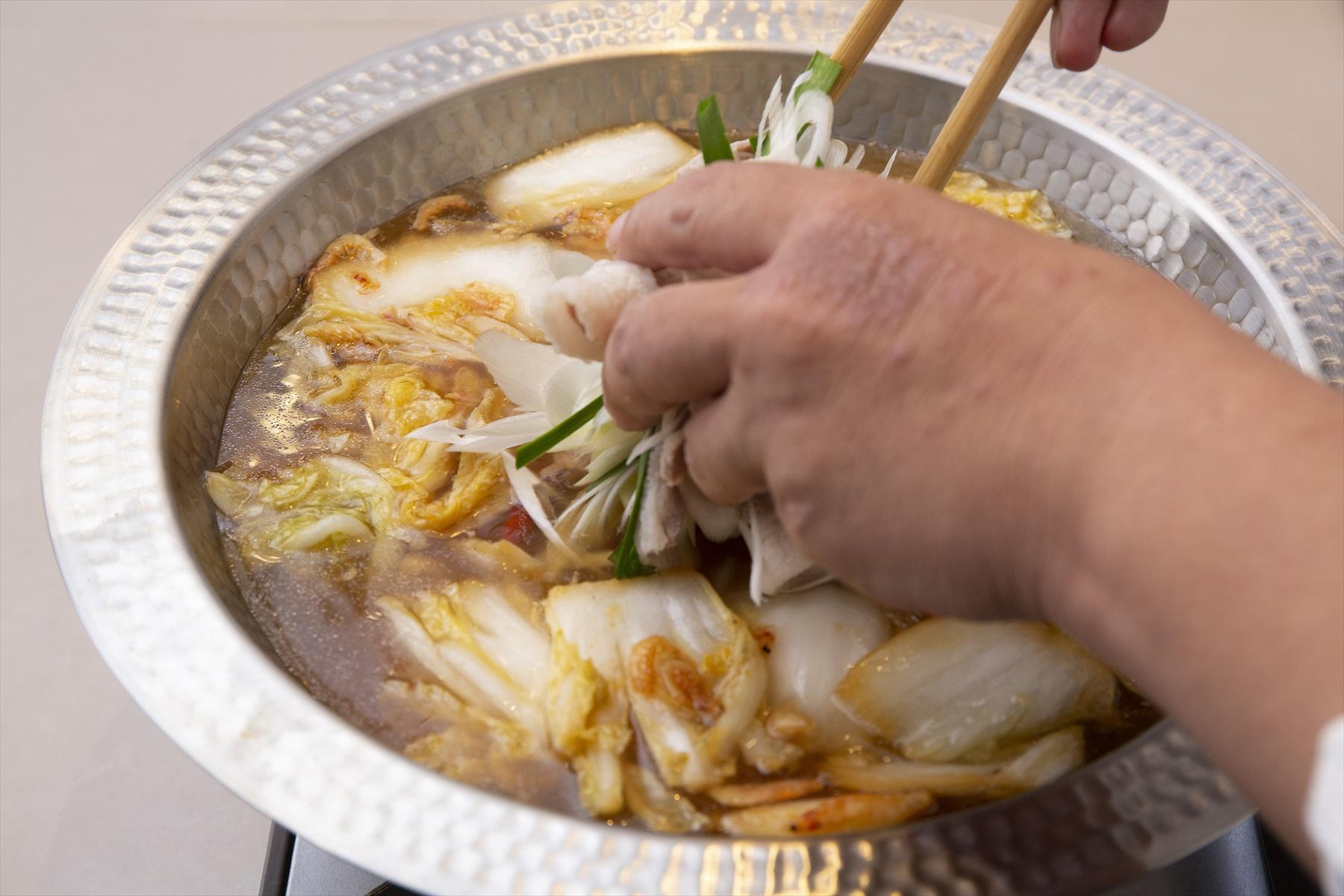 鍋で鶏ガラスープを沸騰させ、具を入れていく