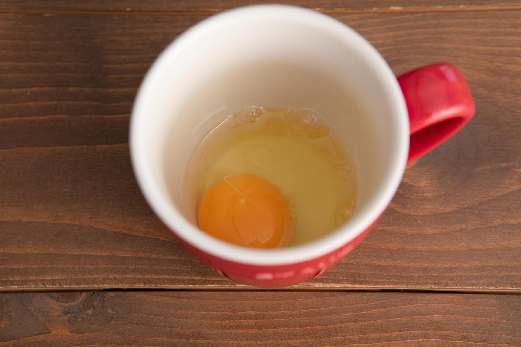 マグカップに卵を割り入れる