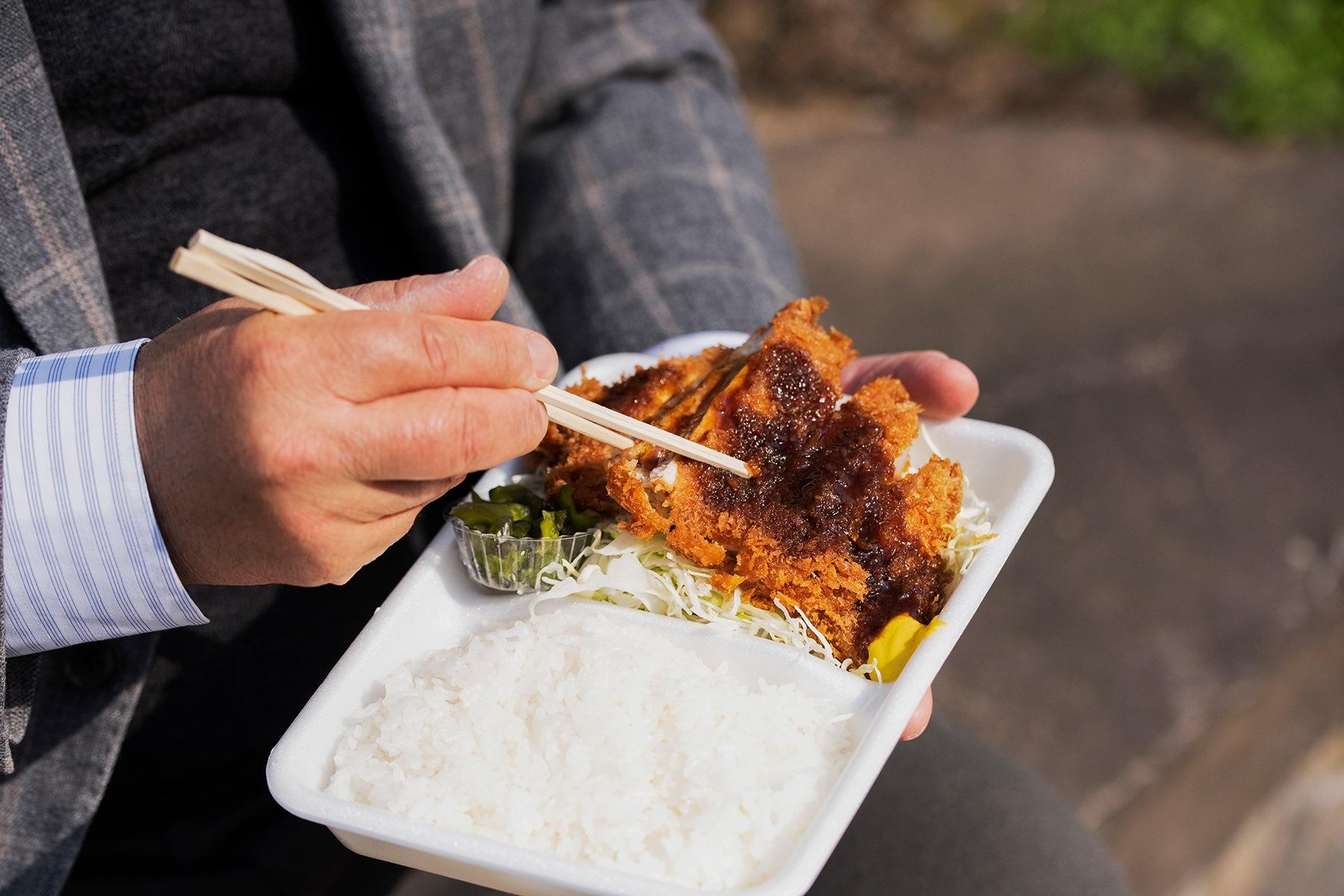 ロースかつ弁当を食べる手