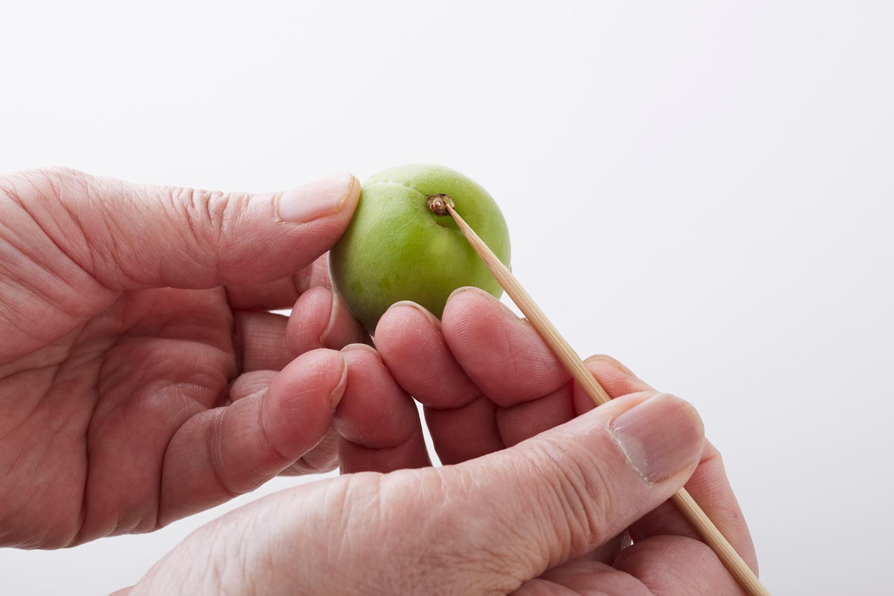 青梅は竹串でへたを取る。