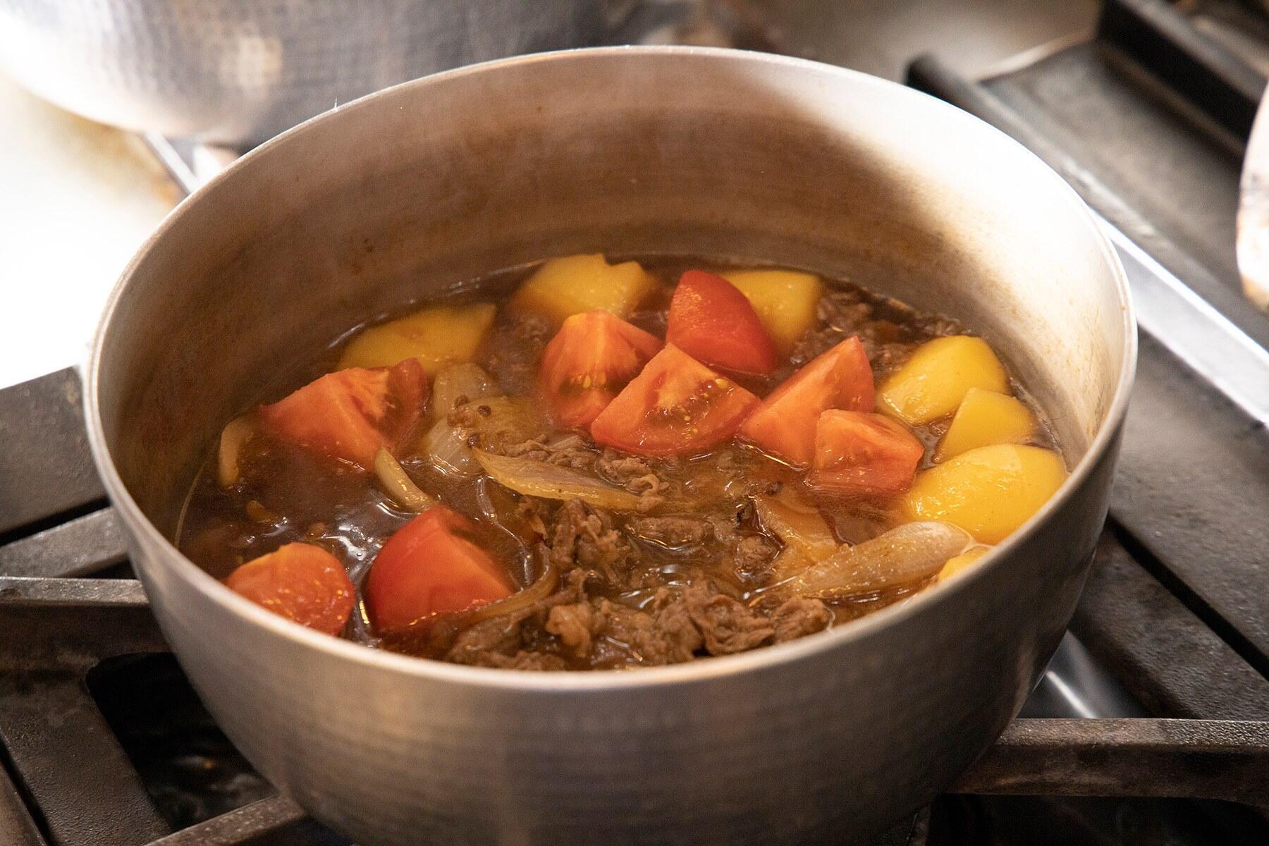 鍋にフライパンの玉ねぎと牛肉、乱切りにしたトマトを加えて7~8分煮る