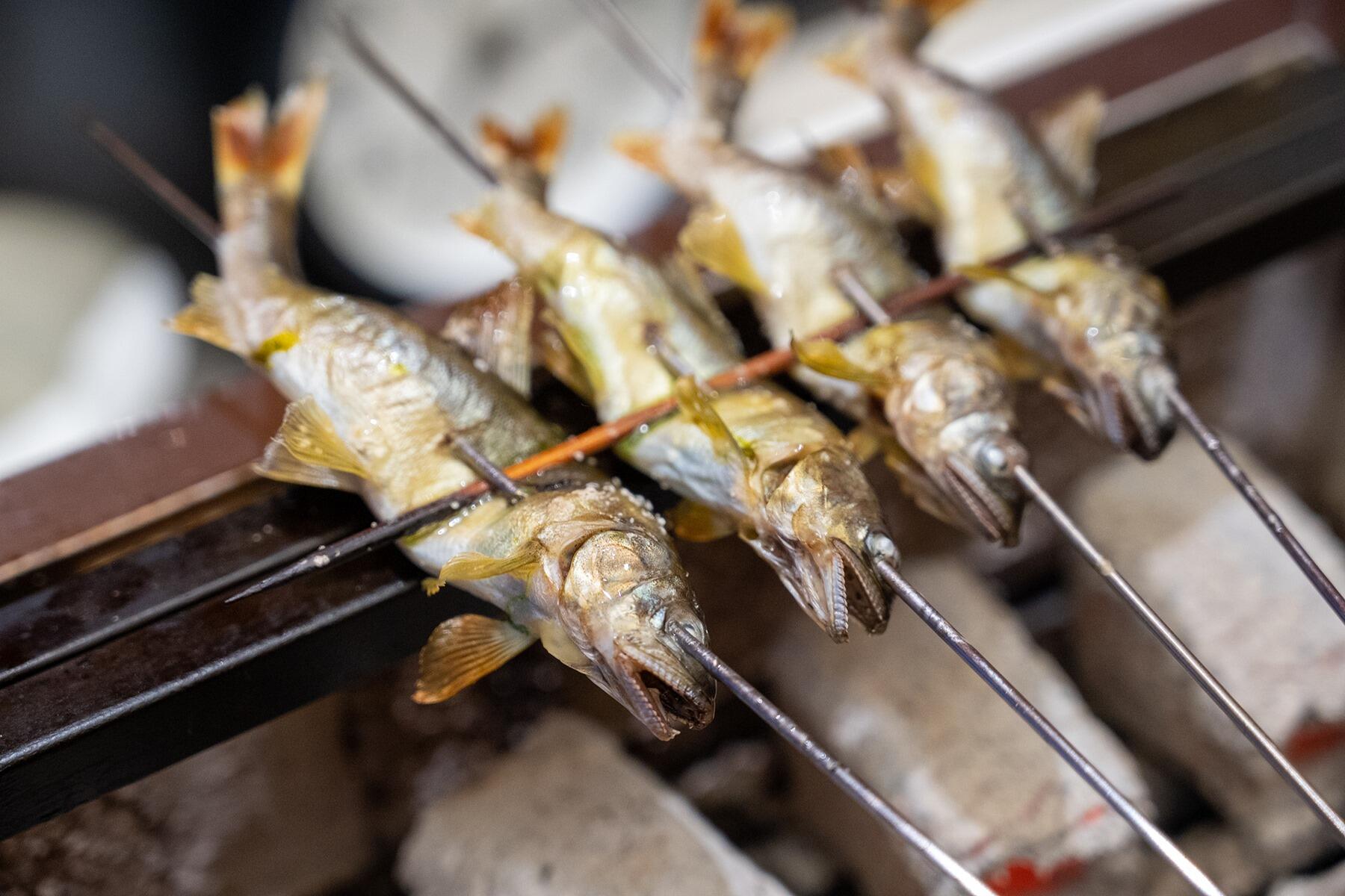 魚を串に刺してあぶっている様子