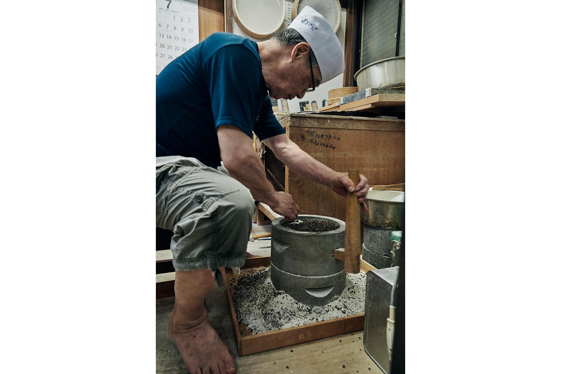 臼で粉を挽く男性