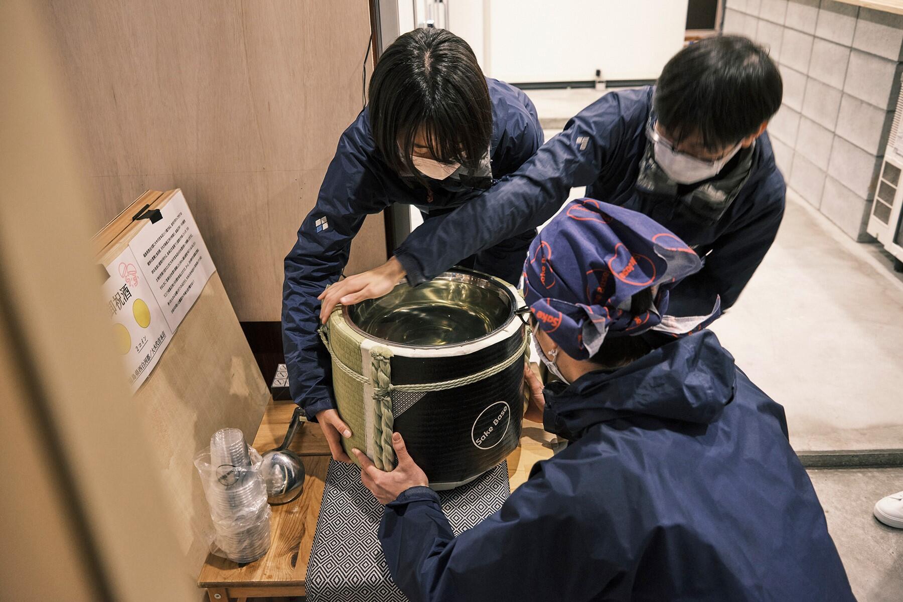 3人がかりで4斗樽を入口付近に設置