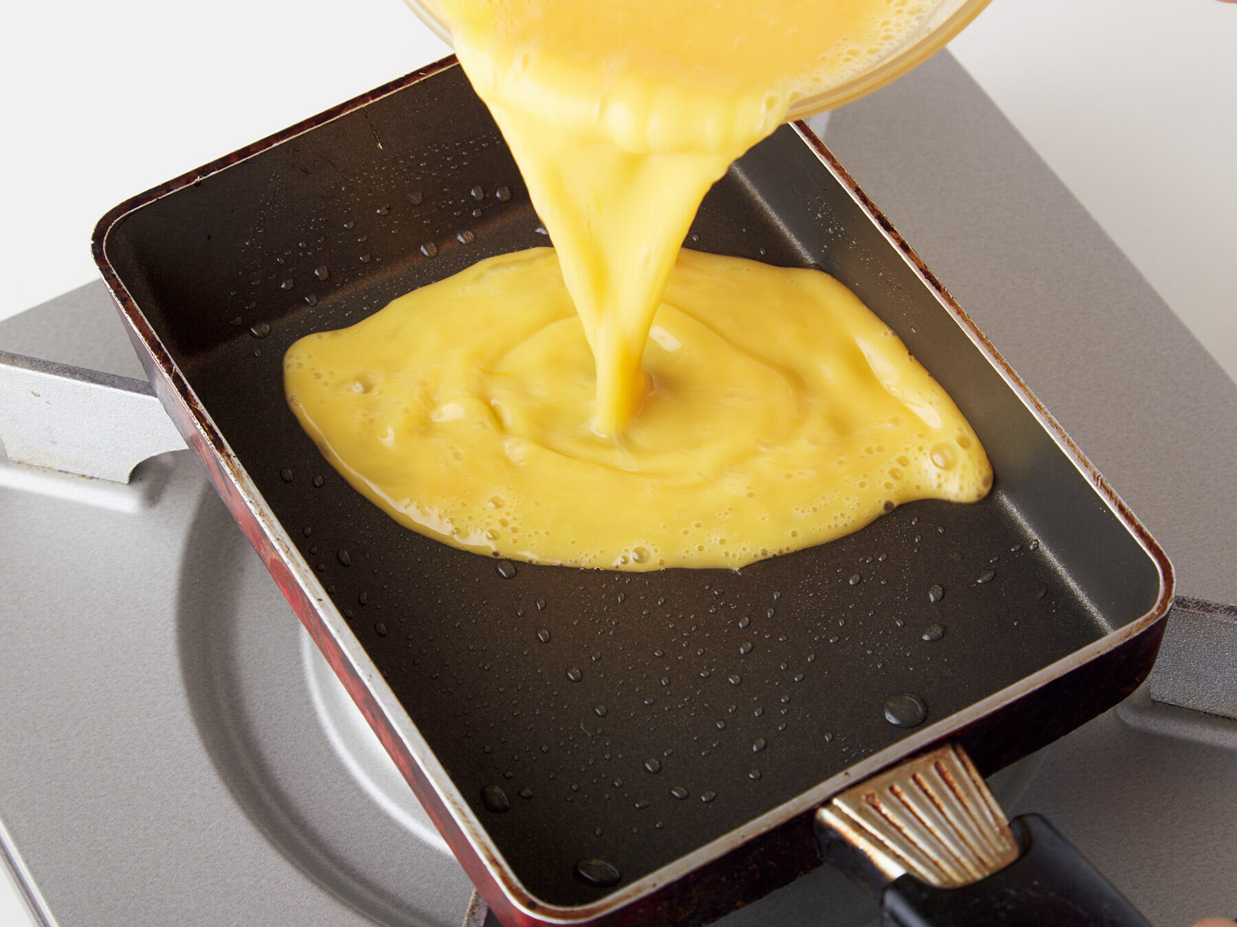 卵焼き器に卵液を流し入れる