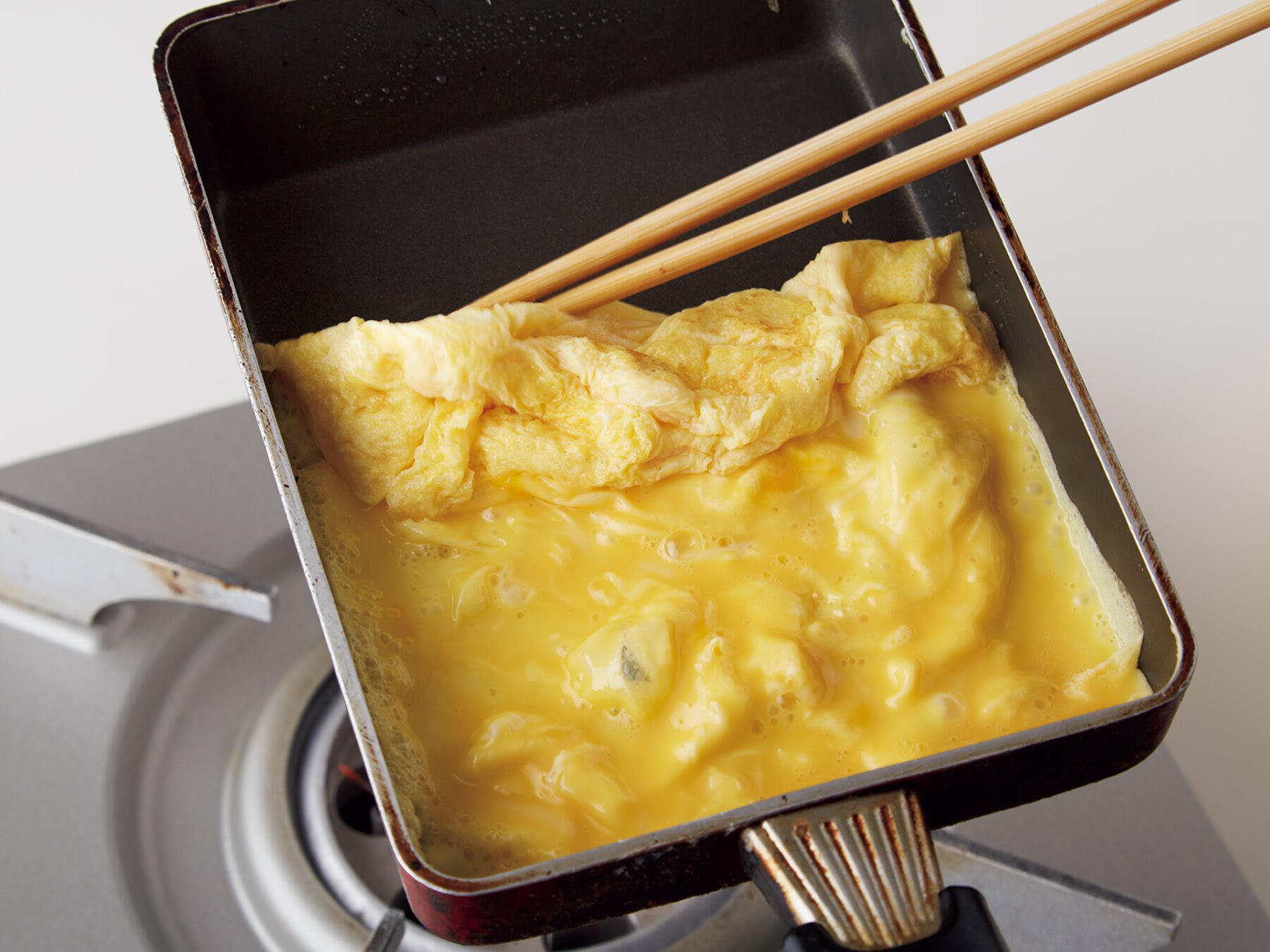 卵焼き器に卵液を流し入れる