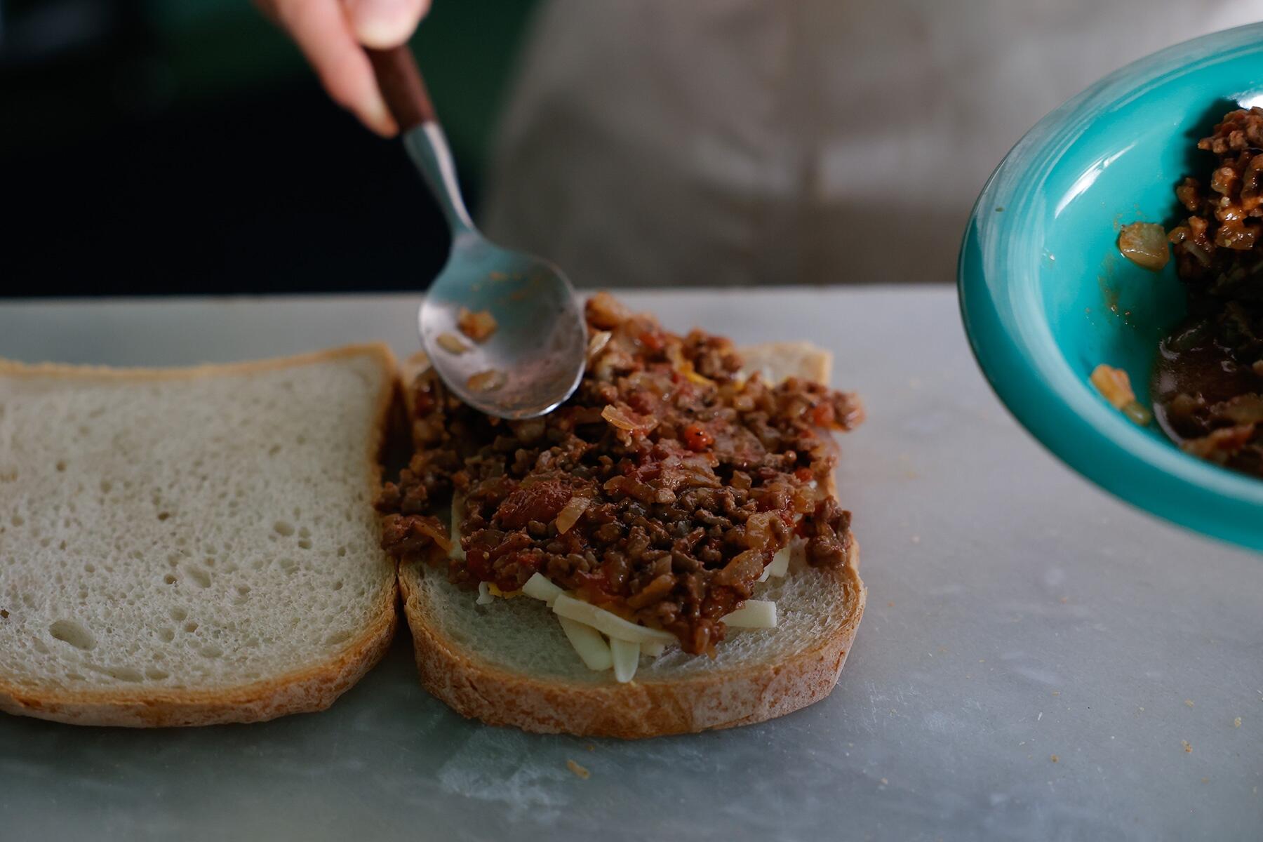 パンにチーズとスロッピー・ジョーをはさむ