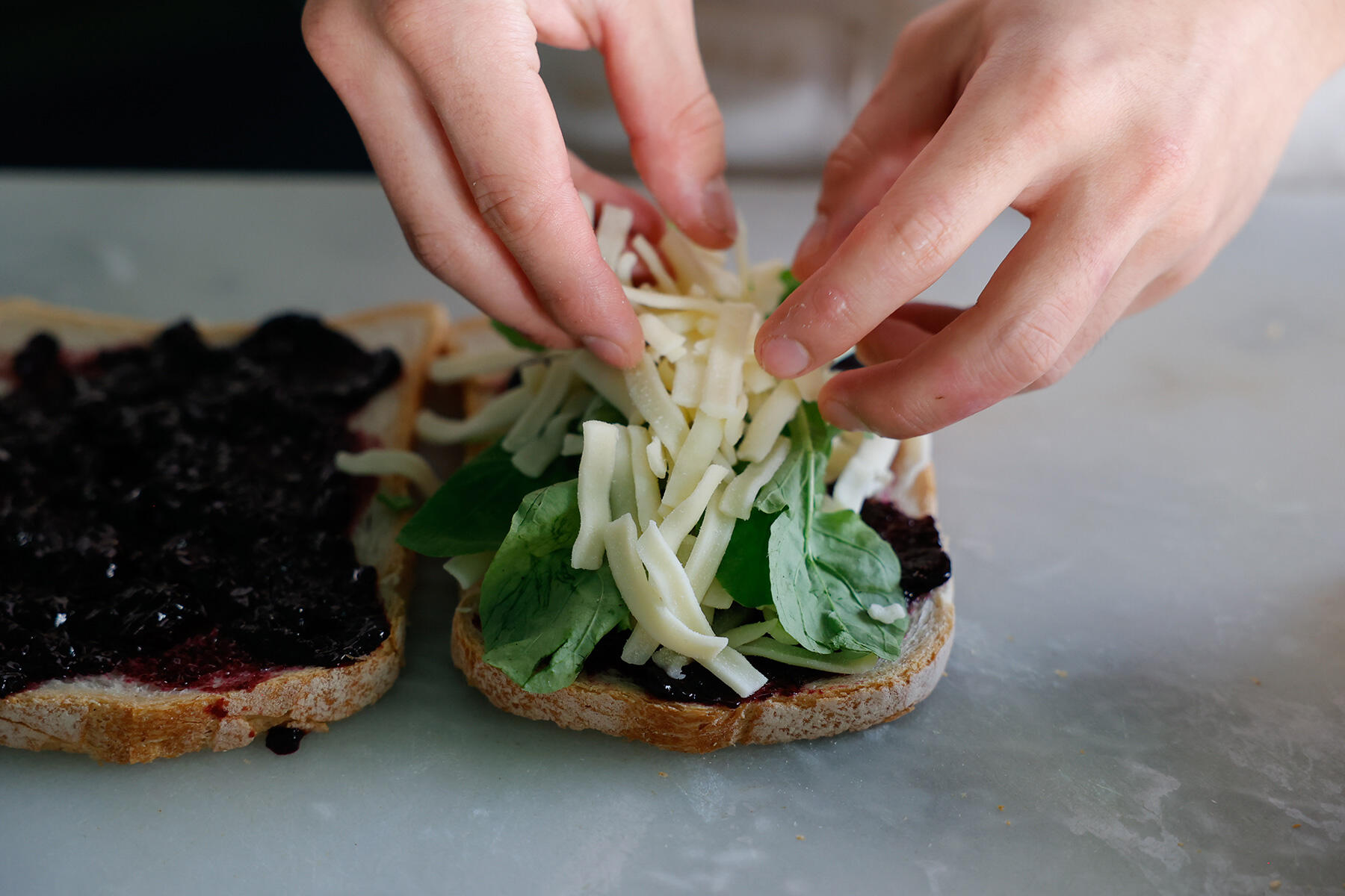 パンにジャムを塗り、チーズ、ルッコラをはさむ