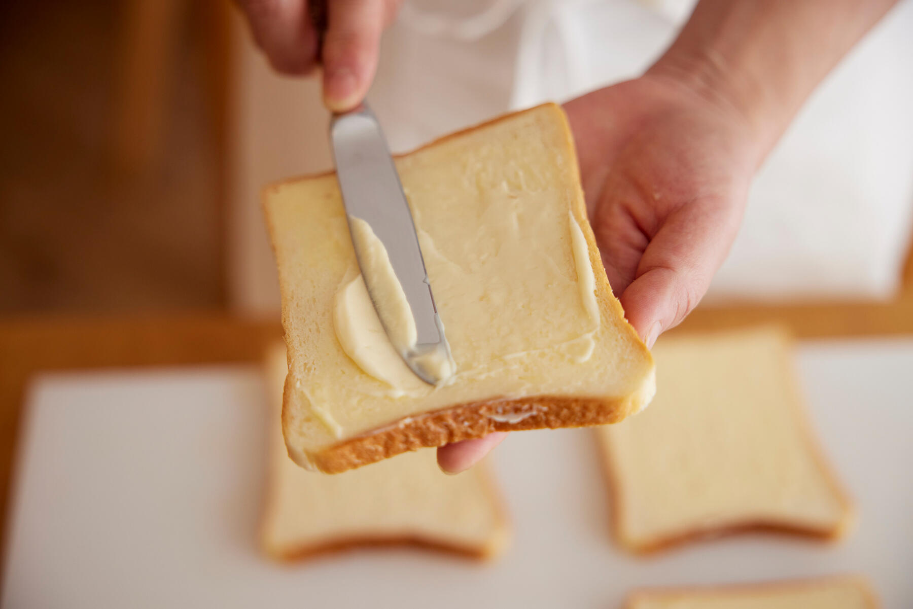 パンにバターとにんにくマヨネーズを塗る