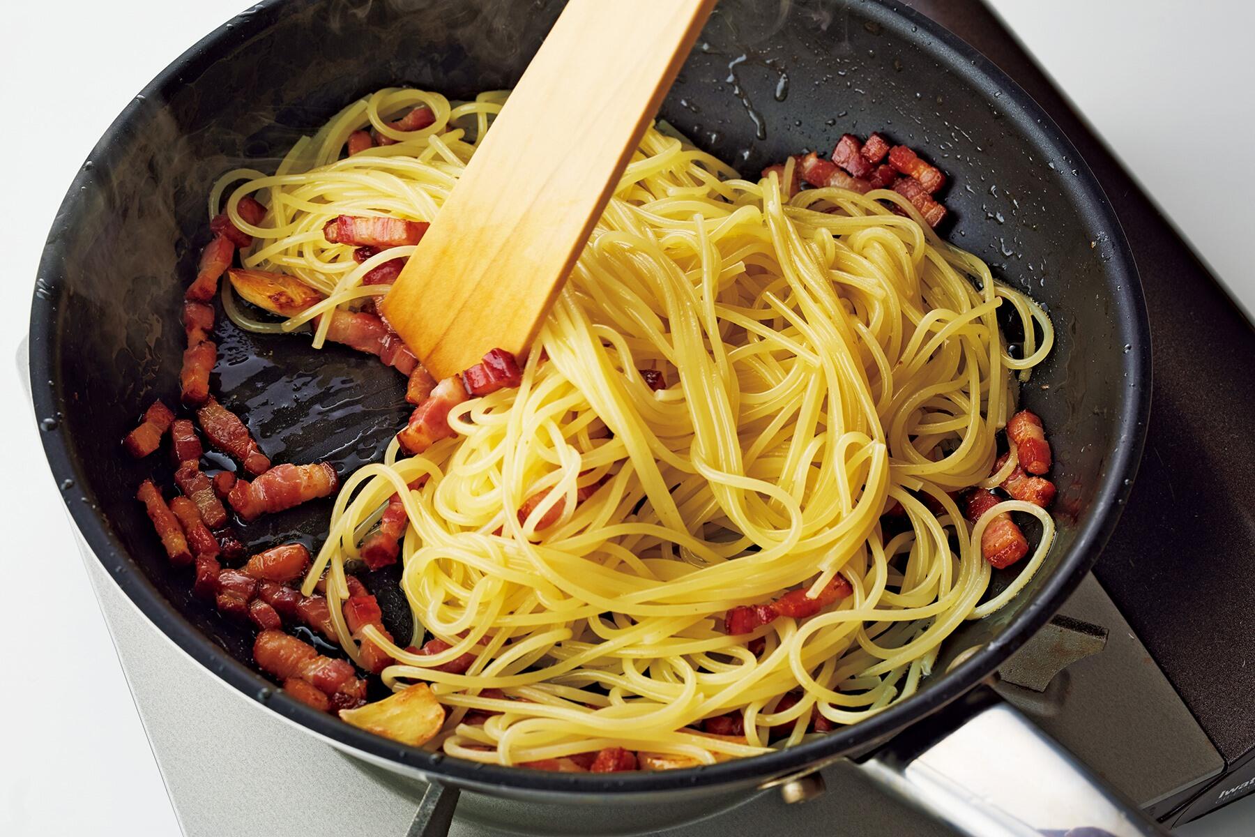 ベーコンとスパゲッティを炒め合わせる