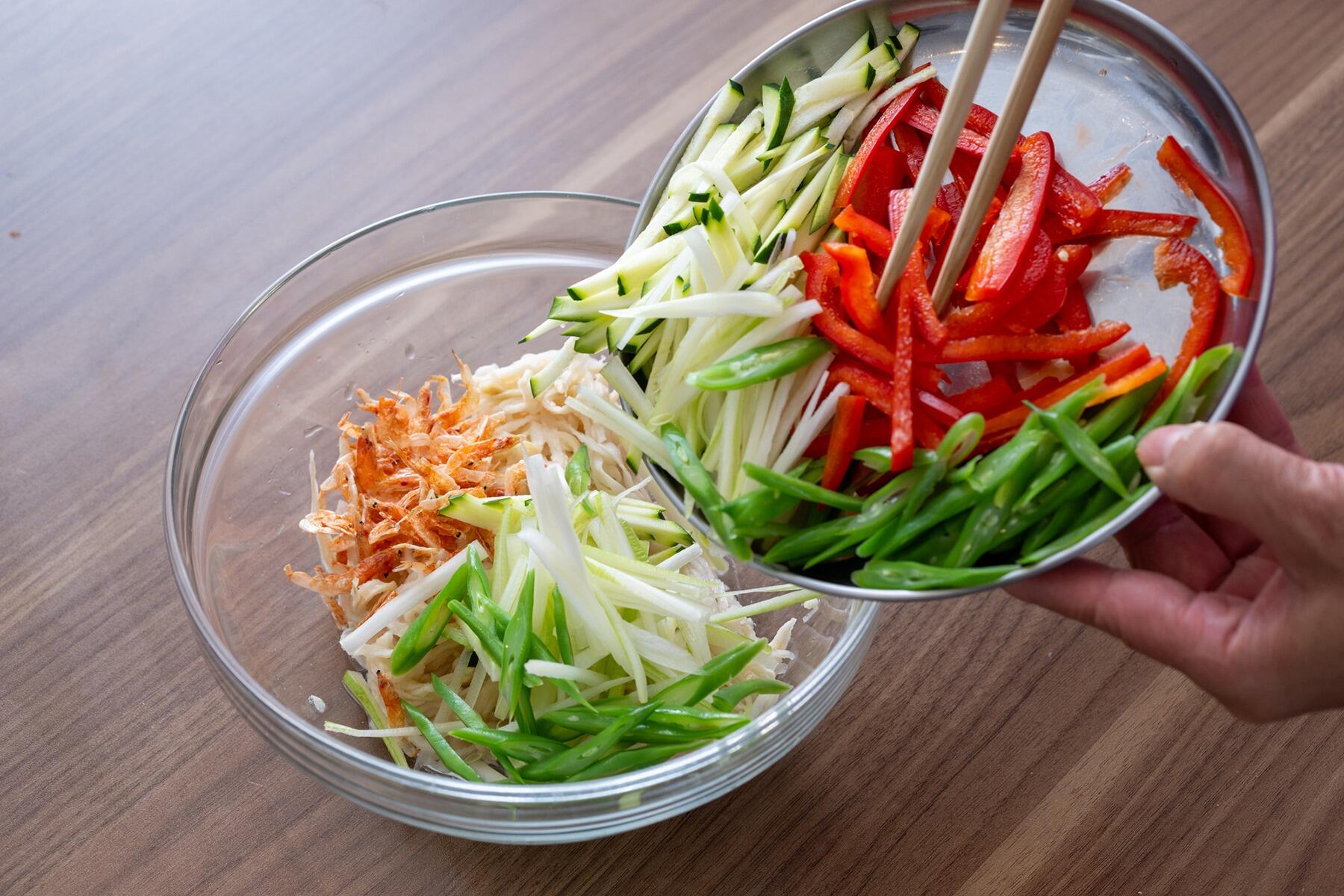 保存がきくからと、買いおきしがちな“切り干し大根”。油断していたらとっくに賞味期限切れ、しかも変色してした……というのは、乾物あるある。しかも、煮物以外になかなかレシピが思い浮かばず、使い切るのが難しいと感じている人も多いはず。尾身さんは切り干し大根、いつもどうやって食べてますか? 「うちでは意外と、煮物以外の料理にすることが多いんです。よくつくるのは、ハリハリ漬け。炒め物にしてもおいしいんですよ。和食のイメージが強いと思うんですが、今回はエスニック料理に使います!」 そう話しながらつくってくれたのは、なんとタイ料理では定番の“ソムタム”。本来は青パパイヤのせん切りを使うサラダで、ナンプラーや唐辛子をきかせた甘酸っぱいタレで和える。尾身さんは、なかなか手に入れにくい青パパイヤのかわりに、切り干し大根を使うというわけなのだ。 「シャキッとした食感がソムタムにぴったりなんです。しかも、切り干し大根は水でもどすだけ。青パパイヤを切る手間いらずで、おいしく食べられるんですよ」 確かに、切り干し大根は水でもどせば火を通さなくても食べられるので、災害の備蓄にも適しているといわれる。実は手間まで省けてしまう、便利な食材なのだ。