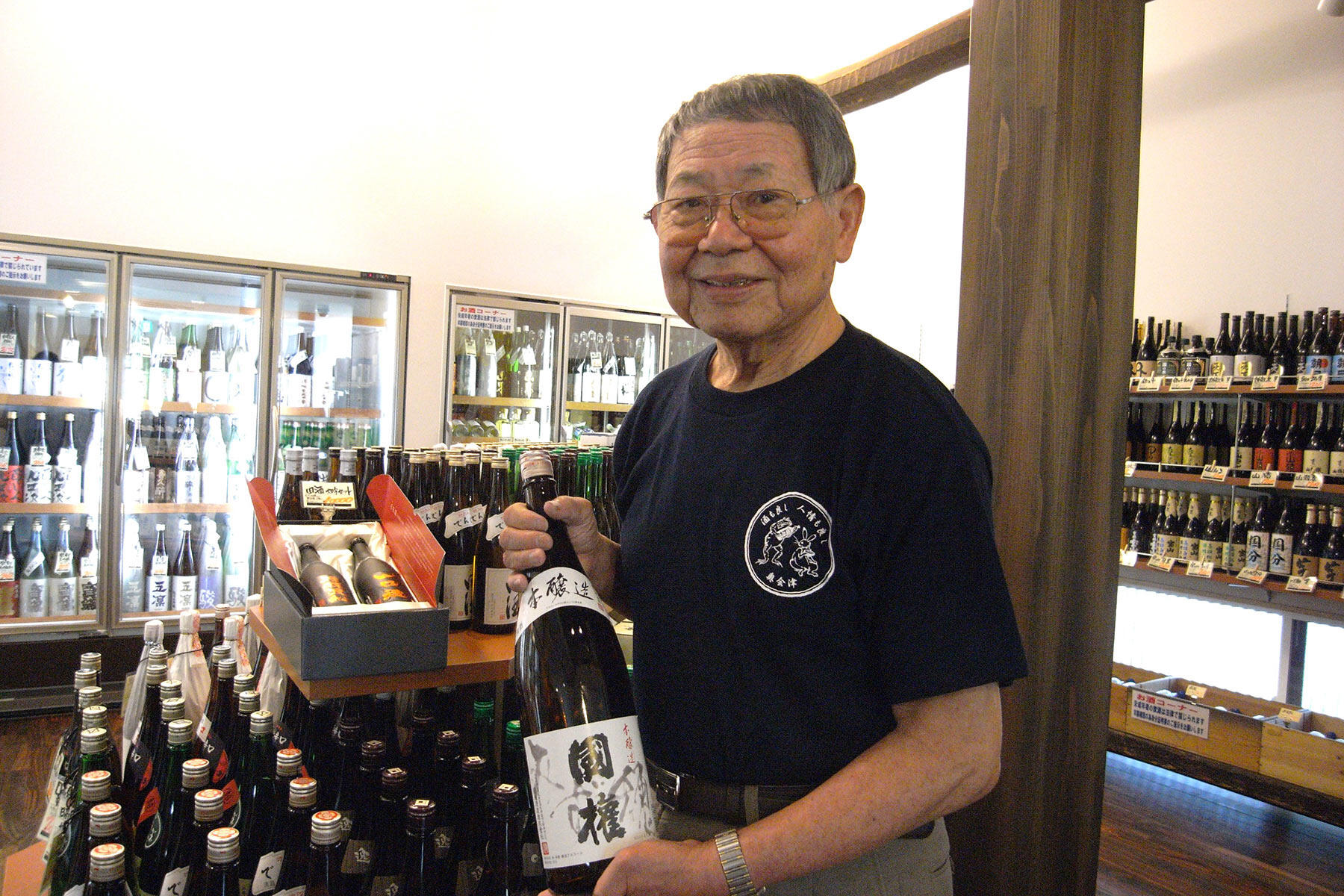 「泉屋の“地酒屋”としてのスタートの酒」と会津田島の「國権」を手にする佐藤隆三さ