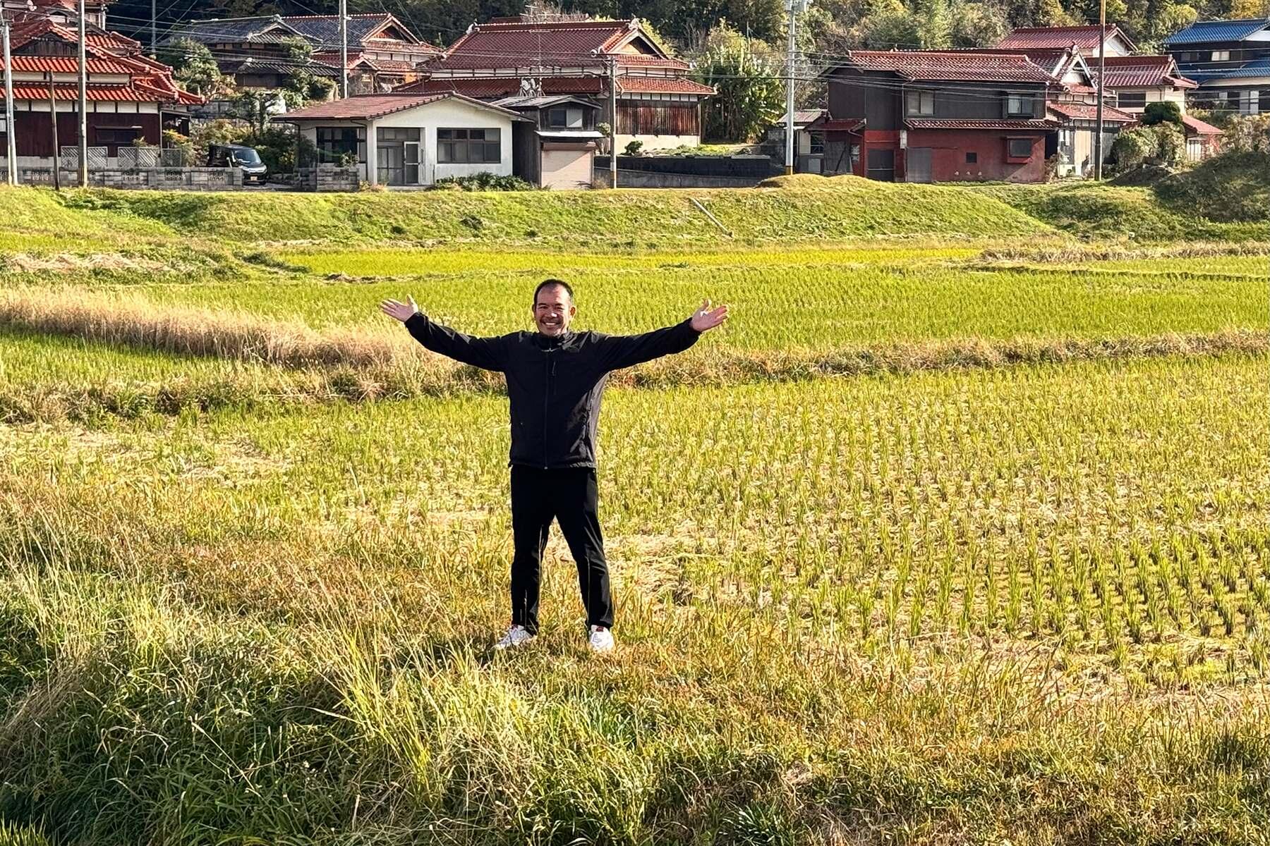 自営田で手を広げて立つ永山さん