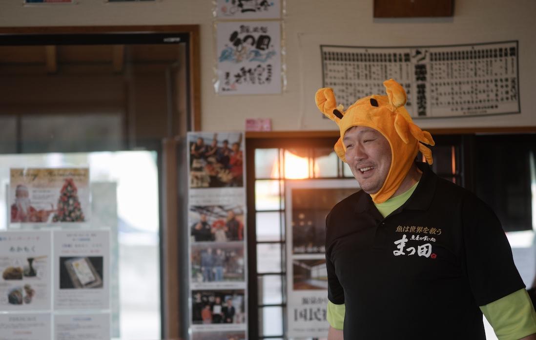 ファンキーなかぶり物で出迎えてくれた店長の枩田（まつだ）卓也さん。「鮮やかな内子は、心ときめく“赤いスイトピー”。“まつ田せいこ丼”はまさに丼界のアイドル。あとは店頭の“渚のバルコニー”で、松田聖子さんご本人に召し上がっていただけたら最高です」。