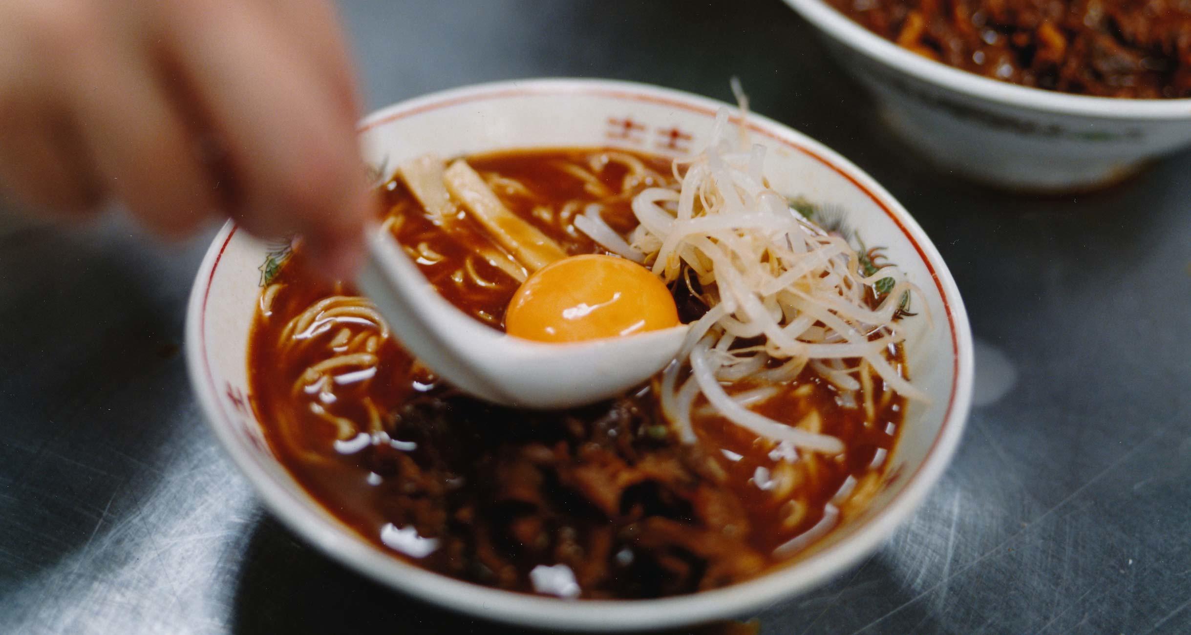 ラーメンに卵の黄身を載せているところ。