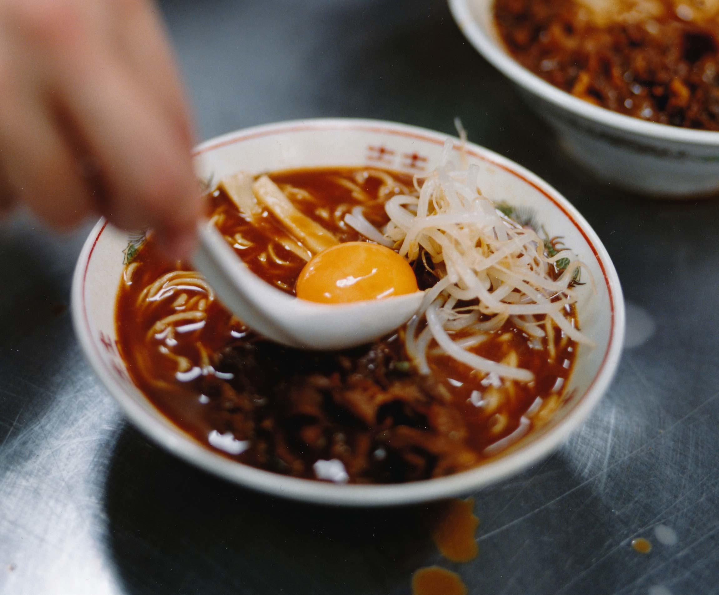 ラーメンに卵の黄身を載せているところ。