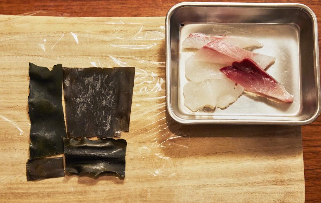 ①ラップフィルムの上に、刺身の大きさに合わせて昆布をパズルのように並べる。