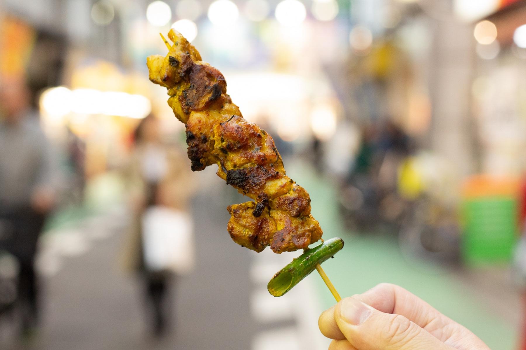 「ナスコ フードコート」のBBQチキン。店頭で食べれば100円也。夕方の店前の人だかりが、そのおいしさを物語ります。肉汁ストッパーの青ネギが親切。