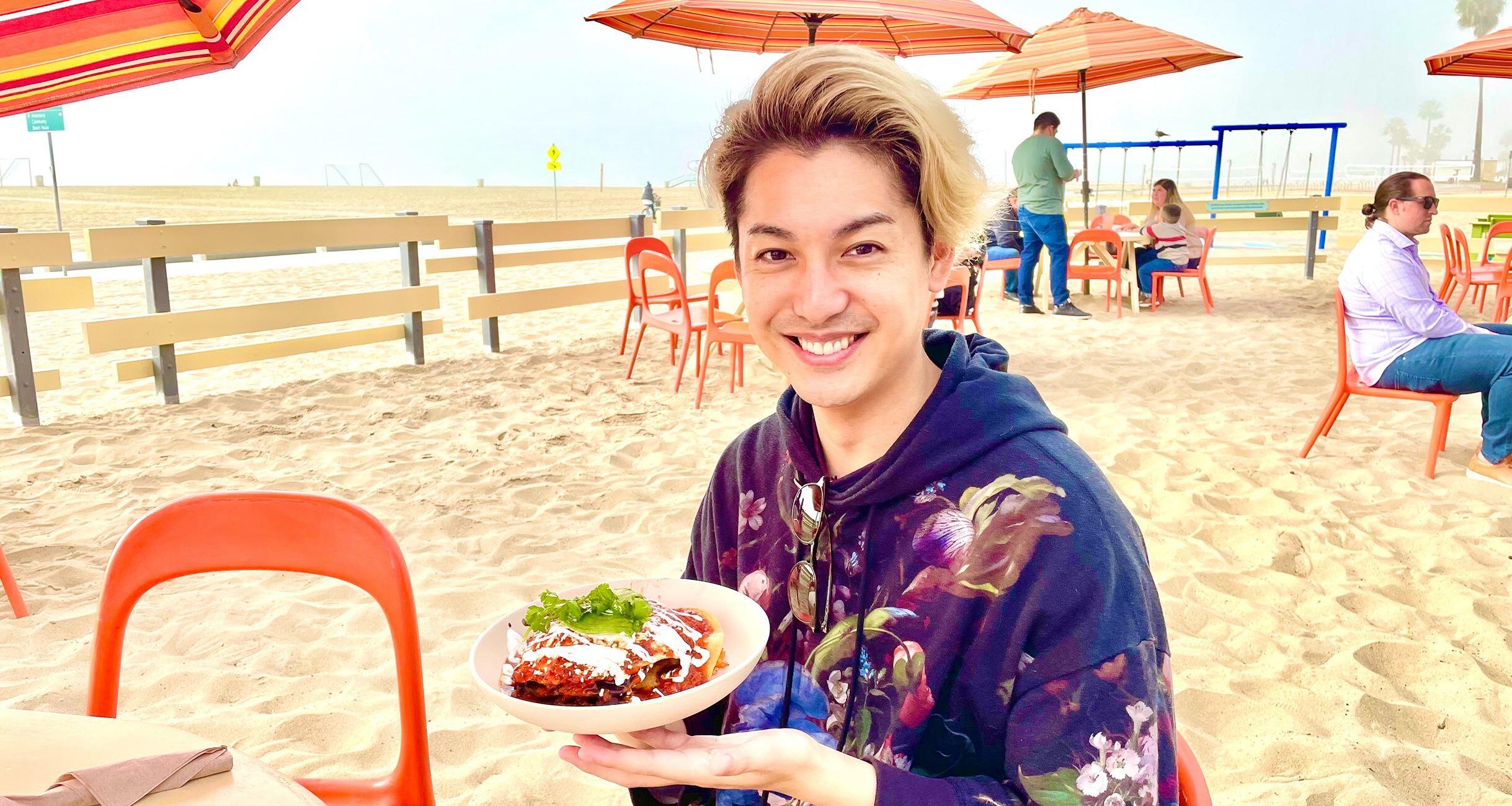 ビーチでプレートを持つ大野さん