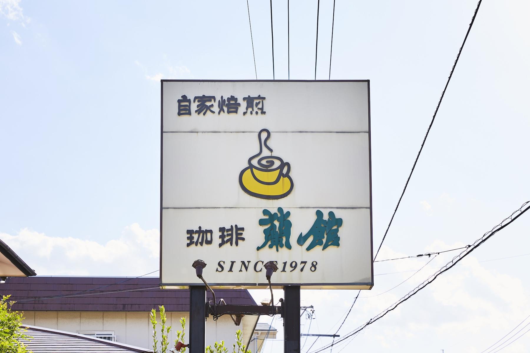 目印は昭和っぽい雰囲気が微笑ましい看板。店の内外には、歴代のお客さまによる絵や書、写真などが飾られている。お手洗いに飾ってある順子さんが活ける季節の花も楽しみのひとつ。