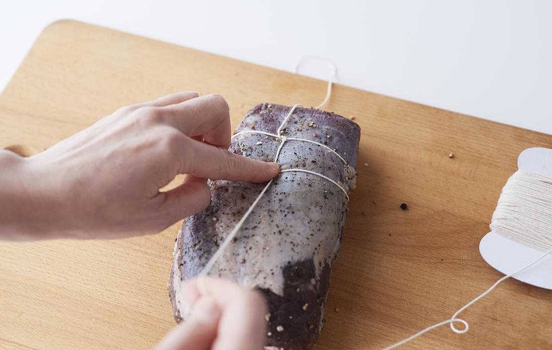 5、長く伸びている糸を引いて、牛肉に食い込まない程度に引き締める。1cmの間隔を空けながら、牛肉の端まで3~5を繰り返して縛る。